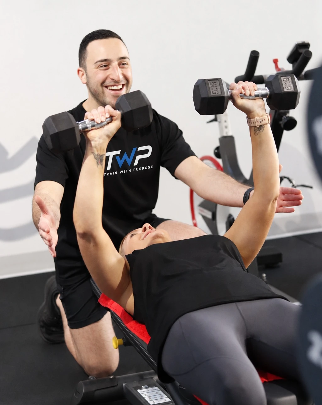 A TWP coach supporting a member during a dumbbell strength exercise